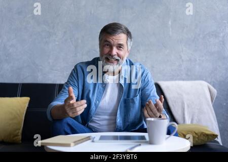 Happy senior retired man blogger looking at camera recording vlog, webcamera view portrait Stock Photo