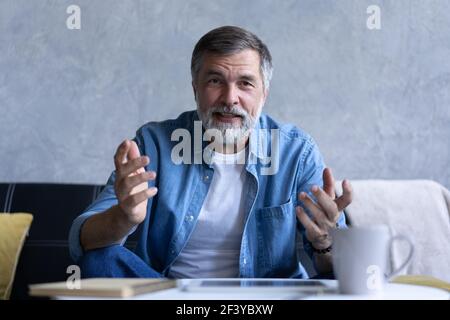 Happy senior retired man blogger looking at camera recording vlog, webcamera view portrait Stock Photo