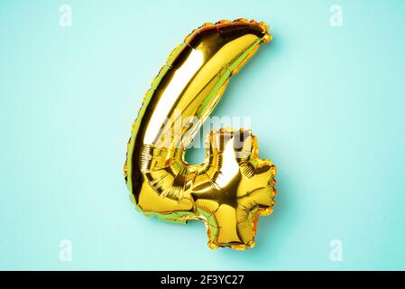 Creative layout. Golden foil balloon number and digit four 4. Birthday greeting card. Anniversary concept. Top view. Copy space. Stylish gold numeral Stock Photo