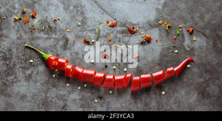 Chopped and Whole Pods of Red Chili Peppers on a Dark Background. Focus in Centre of Image. Stock Photo