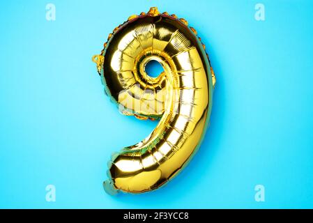 Creative layout. Golden foil balloon number and digit nine 9. Birthday greeting card. Anniversary concept. Top view. Copy space. Stylish gold numeral Stock Photo