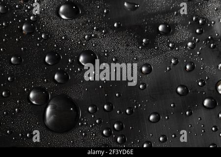 Water drops on the surface covered with foil. Surface tension. Stock Photo