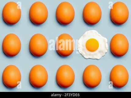 Top view of creative pattern made of brown eggs and a fried egg on a blue background Stock Photo