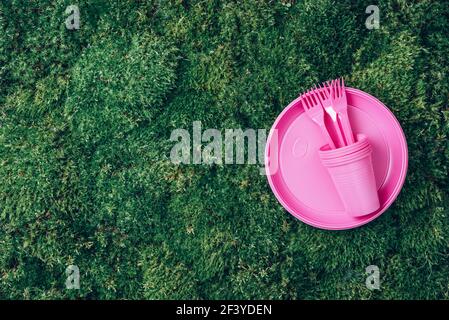 Recycling plastic and ecology. Disposable plastic tableware - plates, forks, spoons, knives. Top view. Copy space. Environmental pollution. Pink Stock Photo