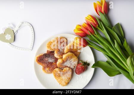 on a white background cheesecakes in the form of hearts on a white plate next Stock Photo