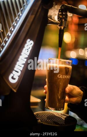 Bucharest, Romania - February 25, 2021: Illustrative editorial close up image of a bartender pouring a pint of Guinness beer in a pub. Stock Photo