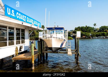 Naples, USA - April 30, 2018: US Coast guard auxiliary building sign for coastal guard patrol with boat dry docked at jetty dock in Florida Gulf of Me Stock Photo