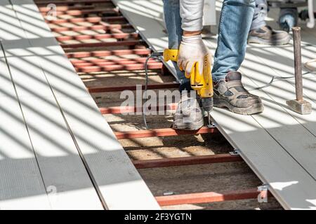 Man assembling composite deck using cordless screwdriver. Stock Photo