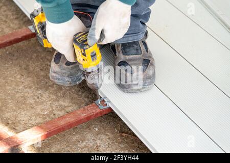Man assembling composite deck using cordless screwdriver. Stock Photo