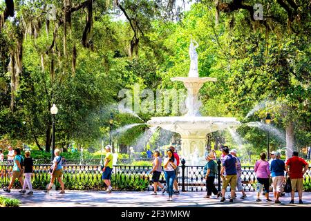 Savannah, USA - May 11, 2018: Famous water fountain in Forsyth park, Georgia on sunny summer day with people walking by southern live oak with Spanish Stock Photo