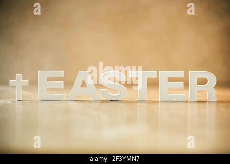 Word Easter made with cement letters on orange marble background. Biblical, spiritual or christian reminder. Christian Easter concept. Crucifixion Stock Photo