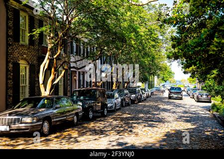 Charleston, USA - May 12, 2018: Downtown city street in South Carolina in southern town with cars parked on empty cobblestone road at sunset Stock Photo