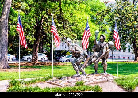 Raleigh, USA - May 12, 2018: North Carolina Vietnam Veteran's Monument memorial with three soldiers carrying rifles, wounded comrade with row of Ameri Stock Photo