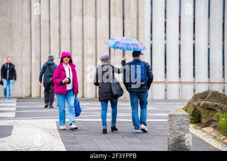 Reykjavik, Iceland - June 19, 2018: People couple holding raining umbrella at rain rainy weather day by Lutheran church of Hallgrimskirkja in downtown Stock Photo