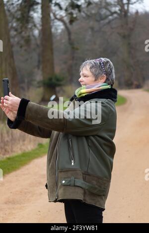 middle aged woman takes selfie in park Stock Photo