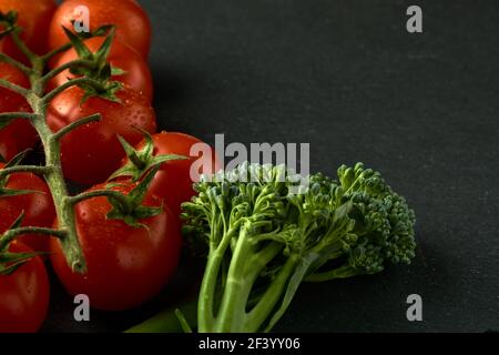 Cherry tomatoes and small broccoli on a black stone table. Image can be used as a texture as well, I left some space for the text on the right side. Stock Photo