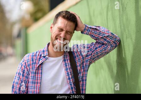 Attractive young man laughing outdoors. Lifestyle concept.. Attractive young man laughing outdoors. Funny guy wearing casual clothes in urban background. Lifestyle concept. Stock Photo