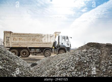 dump truck rides on a construction site. Large piles of rubble in the foreground. Stock Photo