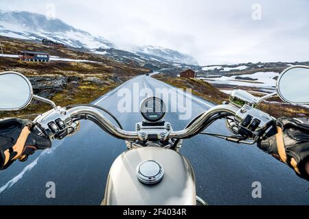 Biker First-person view, mountain pass in Norway. Biker rides a motorcycle on a slippery road through a mountain pass in Norway. Around the fog and snow. First-person view. Stock Photo