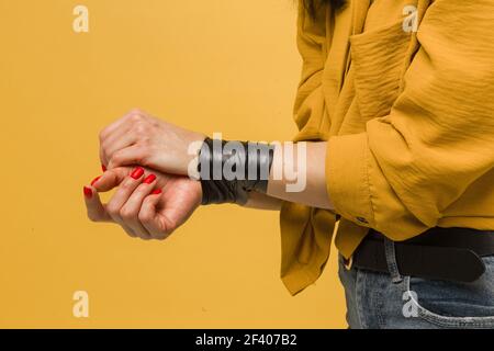 Concept close up photo of female victim with her mouth taped up, kidnapping. Wears yellow shirt, isolated yellow color background Stock Photo