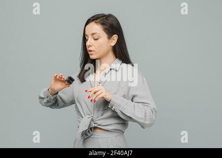 Photo female with pulse oximeter on her finger, checks her health. Wears grey dress, isolated grey color background Stock Photo