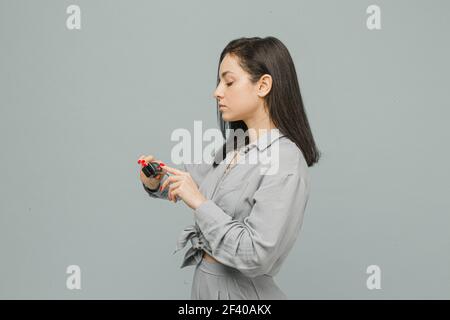 Photo female with pulse oximeter on her finger, checks her health. Wears grey dress, isolated grey color background Stock Photo