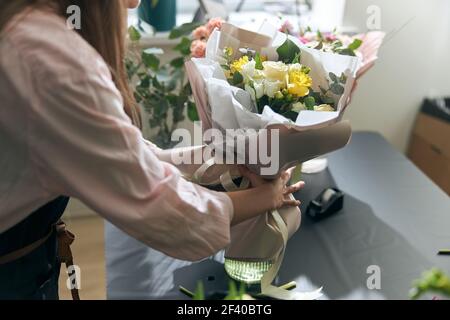 Nice and colorful bouqette of different flowers. Female florist hold it. She is in flower shop. Close up Stock Photo