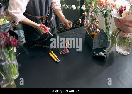 Woman sales flowers in flower shop. Florist woman working at flower shop. Portrait of successful modern florist wearing apron Stock Photo