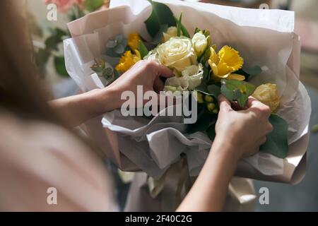 Nice and colorful bouqette of different flowers. Female florist hold it. She is in flower shop. Close up Stock Photo