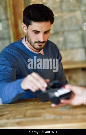 NFC Near Field Communication Mobile Payment. Hand holding smartphone paying on EDC machine. Stock Photo