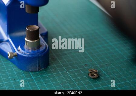 Artisan using hand press for setting snaps in leather for makes a wallet. Hand Pressure Snap Pressing Machine is using by craftsman in leather Stock Photo