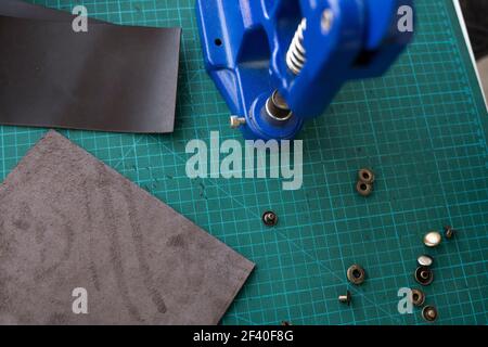 Artisan using hand press for setting snaps in leather for makes a wallet. Hand Pressure Snap Pressing Machine is using by craftsman in leather Stock Photo