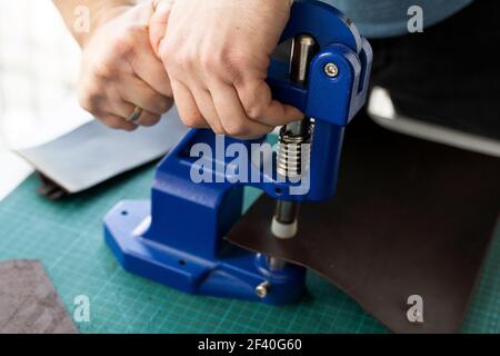 Artisan using hand press for setting snaps in leather for makes a wallet. Hand Pressure Snap Pressing Machine is using by craftsman in leather Stock Photo