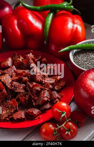 Sun-dried tomatoes with paprikas and chilly peppers on red plate Stock Photo