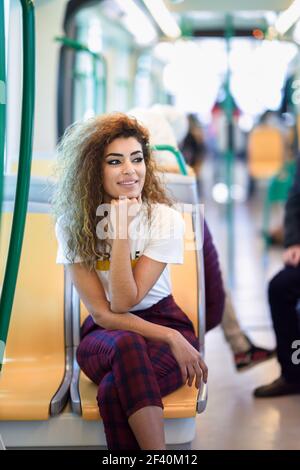 Arabic woman sitting inside subway train. Arab girl in casual clothes near a window.. Arab woman inside metro train. Arab girl in casual clothes. Stock Photo