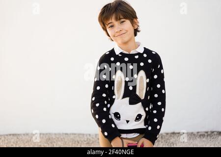 Nice seven years old girl with short hair smiling on camera on a white wall.. Seven years old girl with short hair smiling on a white wall Stock Photo