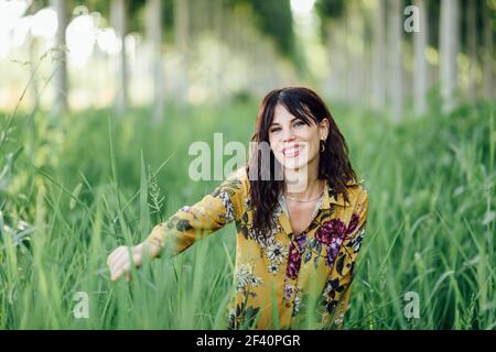 Beautiful hiker young woman, wearing flowered dress, hiking in the countryside.. Young woman, wearing flowered dress, between trees. Stock Photo