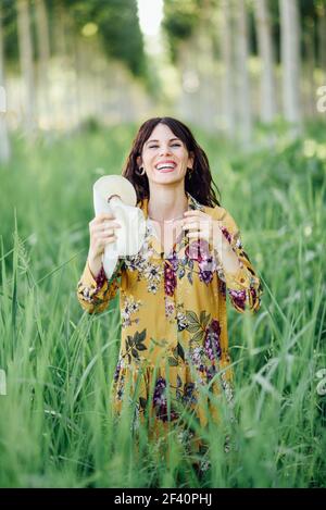 Beautiful hiker young woman, wearing flowered dress, hiking in the countryside.. Young woman, wearing flowered dress, between trees. Stock Photo