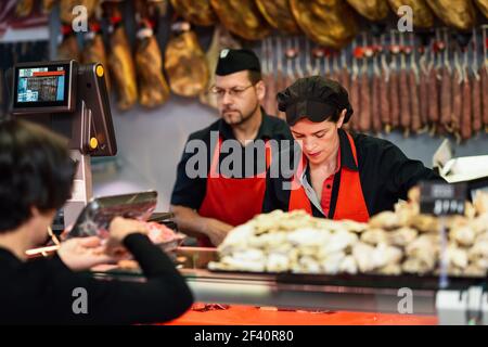 Butchers attending a customer in a butcher&rsquo;s shop weighing the meat and charging. Butchers attending a customer in a butcher&rsquo;s shop Stock Photo