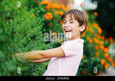 Little girl with very short hair, laughing in an urban park wearing pink dress.. Little girl, eight years old, having fun in an urban park. Stock Photo