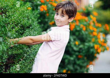 Little girl with very short hair, having fun in an urban park wearing pink dress.. Little girl, eight years old, having fun in an urban park. Stock Photo