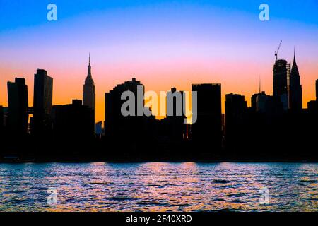 New York City skyline with silhouetted buildings and colorful sunset sky Stock Photo