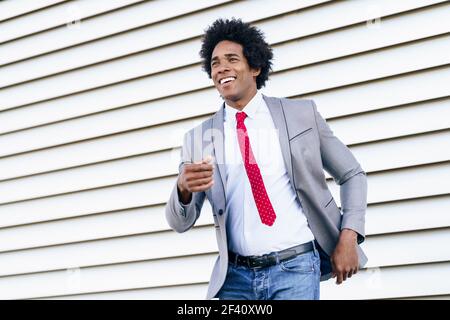 Happy Black Businessman wearing suit dancing outdoors. Man with afro hair.. Happy Black Businessman wearing suit dancing outdoors. Stock Photo