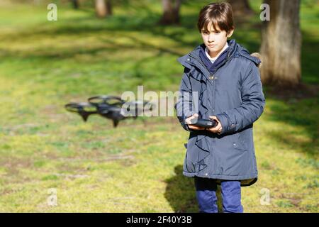 Nine-year-old girl operating toy drone flying or hovering by remote control in a park.. Nine-year-old girl operating toy drone flying by remote control Stock Photo