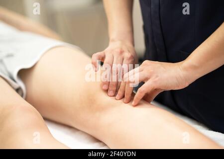 Female Physiotherapist woman doing a treatment on a young woman&rsquo;s knee.. Physiotherapist woman doing a treatment on a woman&rsquo;s knee. Stock Photo