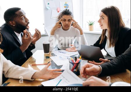 Overworked business partners on briefing meeting can't make a deal or come to agreement. Mixed race coworkers having a conflict, feeling exhausted and frustrated Stock Photo