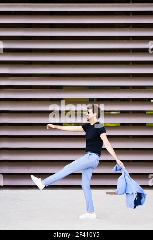 Happy young man walking funny in urban background. Happy man walking funny in urban background Stock Photo