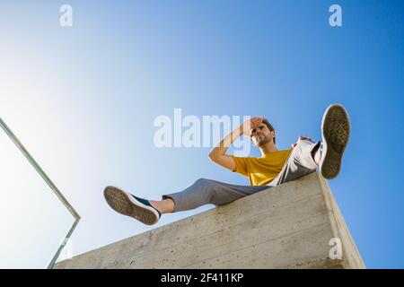 Young man sitting on a ledge looking around. Man sitting on a ledge looking around Stock Photo