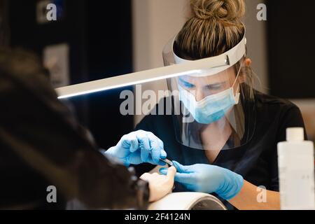 Aesthetician doing the manicure, filing the nails with a file to his client in a beauty center. Business and beauty concepts. Aesthetician doing the manicure, filing the nails with a file to his client in a beauty center Stock Photo