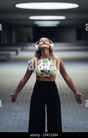 Young woman opening arms wearing headphones in urban background.. Young woman opening arms wearing headphones outdoors Stock Photo
